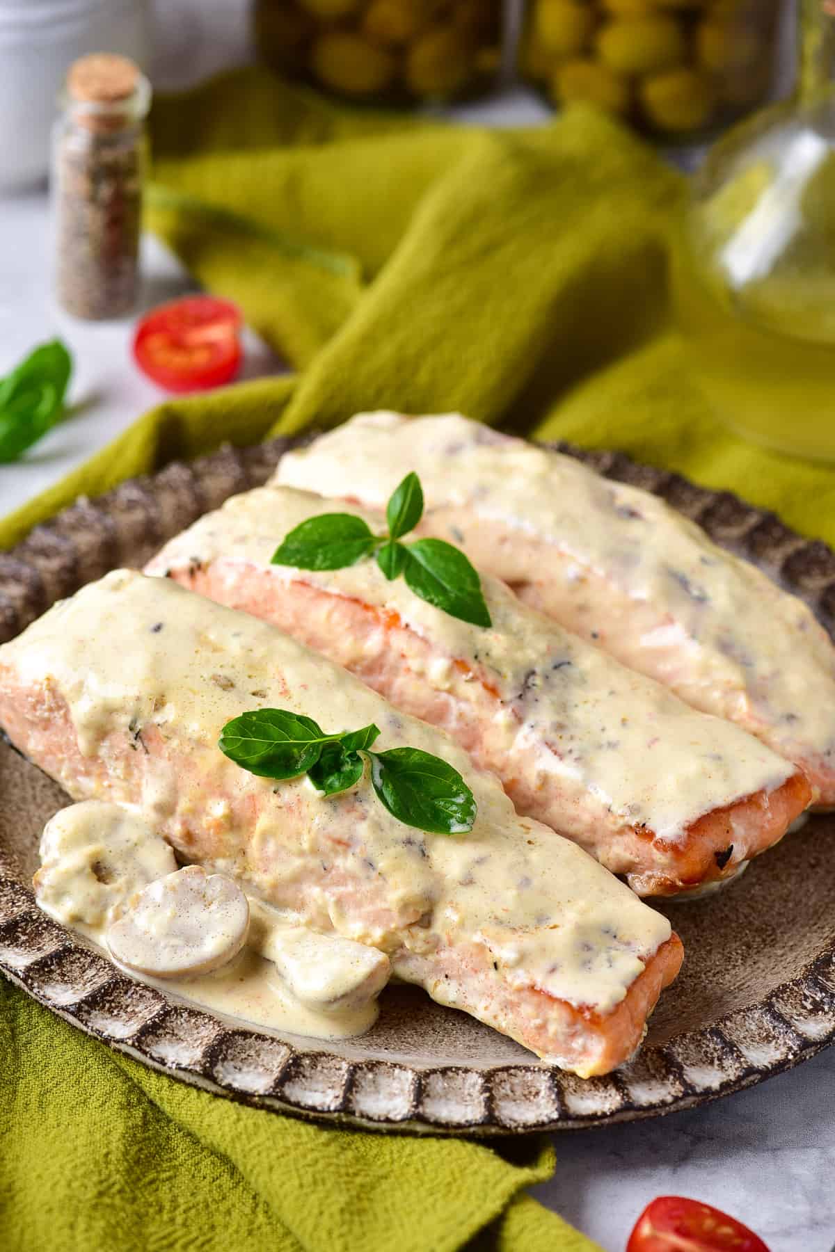 Plate with pan fried salmon covered in creamy mushroom sauce.