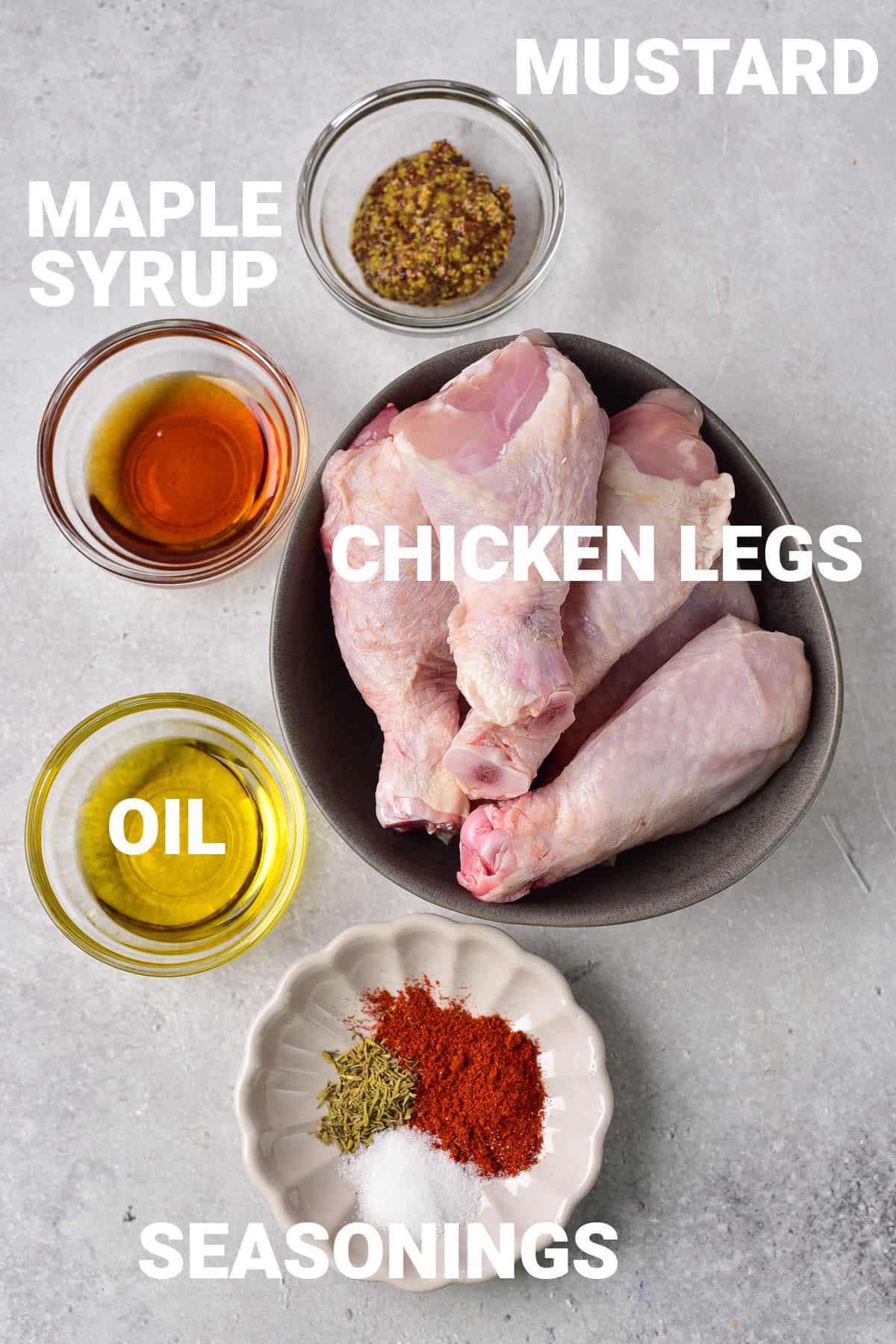 Chicken legs, mustard, maple syrup, oil and seasonings on a table.