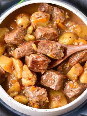 Close up of a dish of beef stew with potatoes and vegetables.