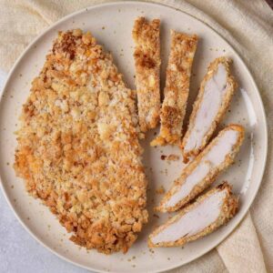 A plate with a breaded chicken cutlet cut into slices.