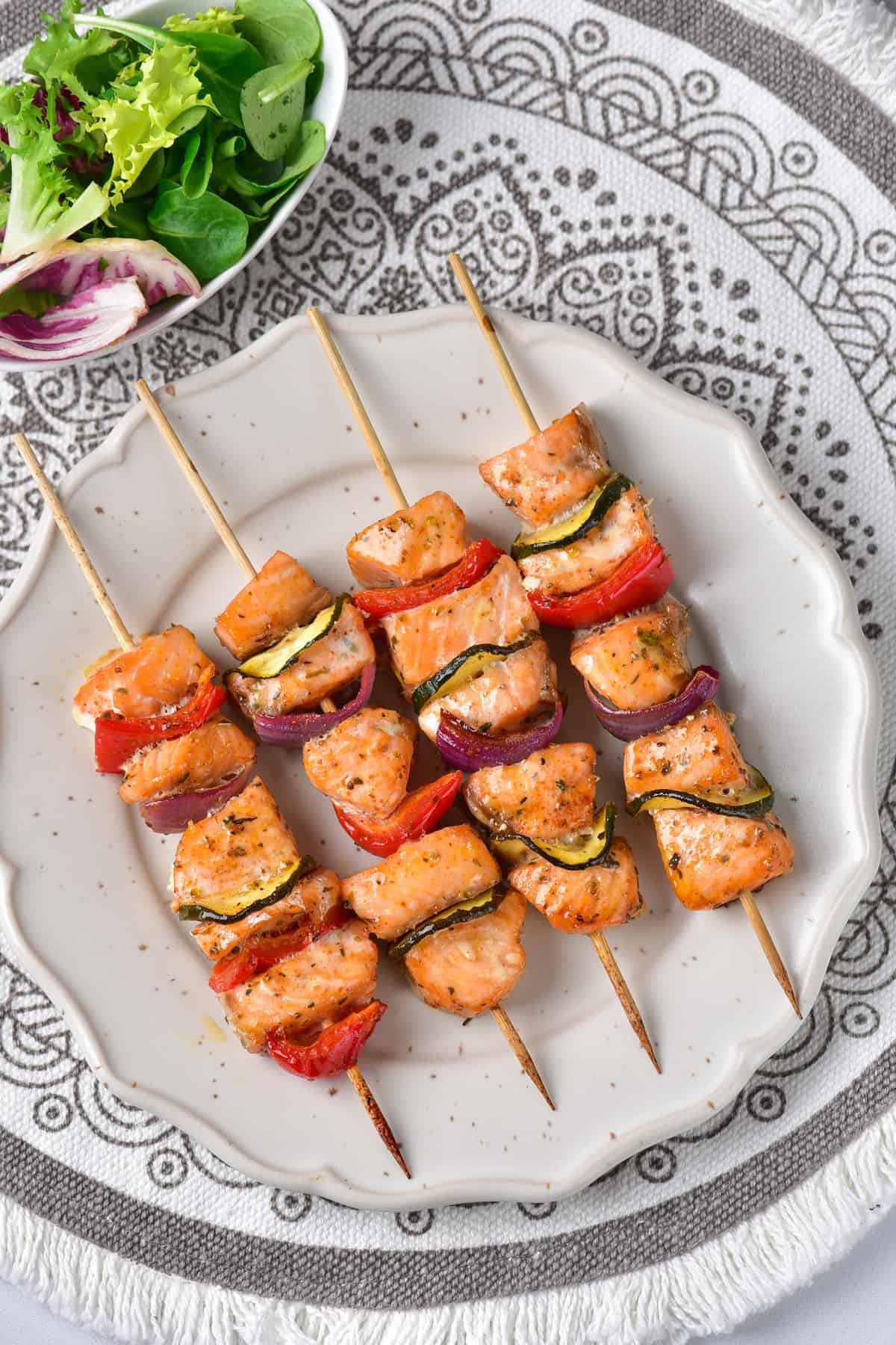 Table with a plate of vegetable salmon kabobs.