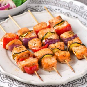 Plate of salmon kabobs with mediterranean vegetables.