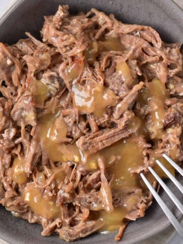 Close up of a dish of copycat Cracker Barrel roast beef covered in gravy.
