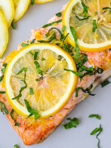 Plate with a slice of old bay salmon with two lemon slices on top.