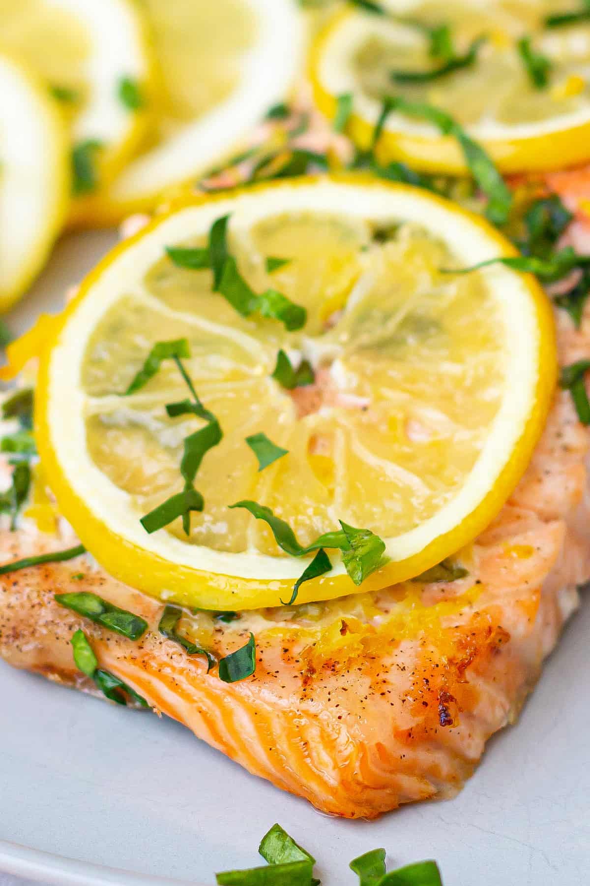 A slice of Old Bay Salmon topped with sliced lemons and herbs.