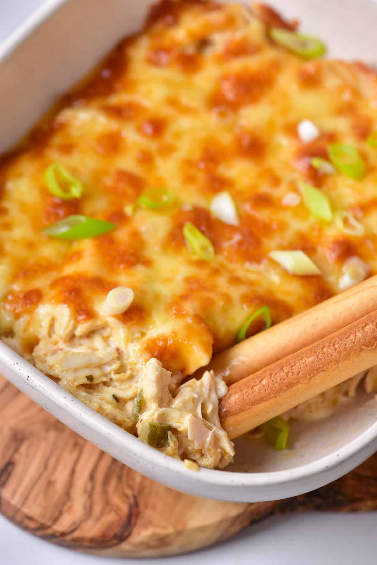 Breadsticks in a dish of baked buffalo ranch chicken dip.