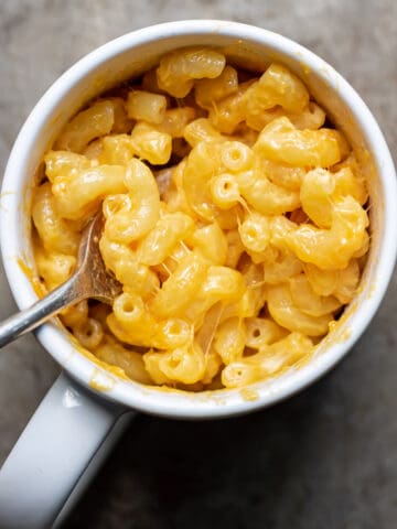 Mac and cheese in a mug with a fork.