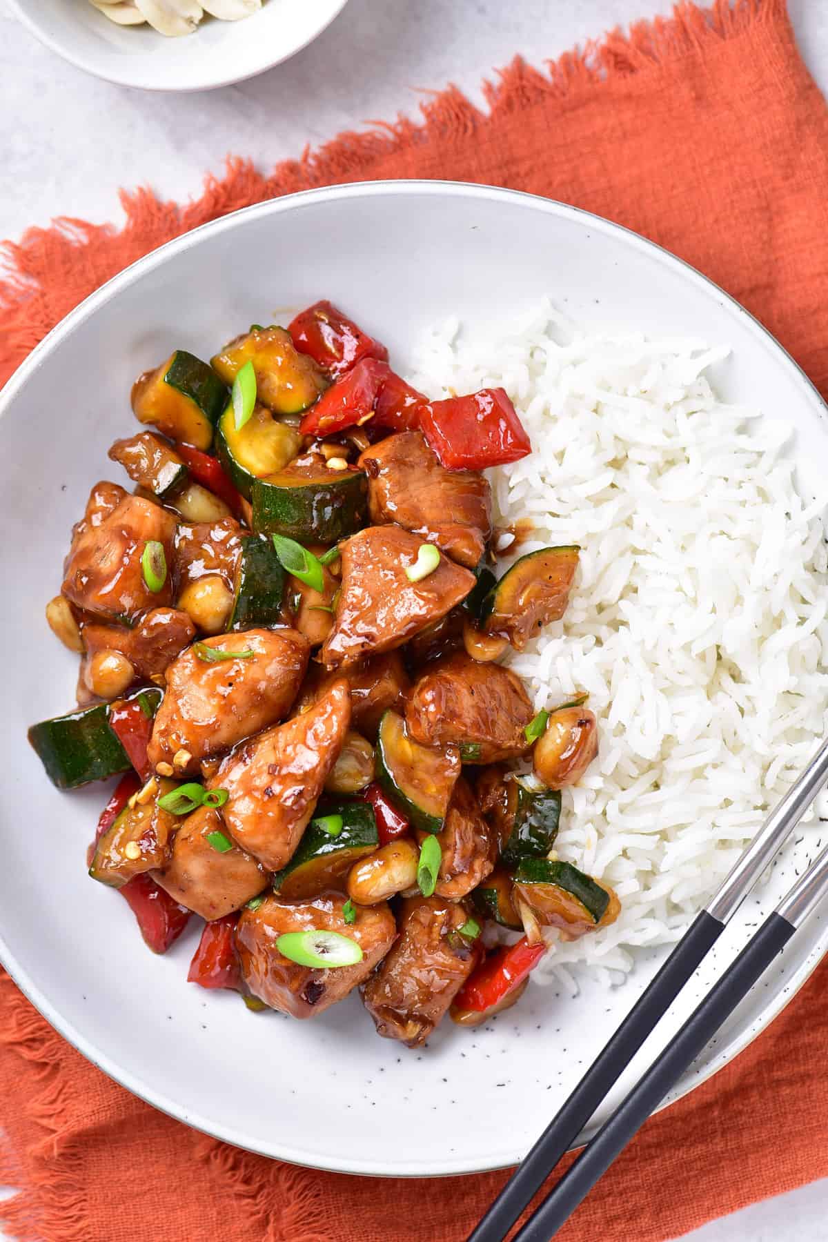 Table with a plate of Kung Pao Chicken over rice.